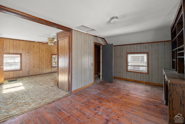 spare room with attic access, visible vents, wood walls, and hardwood / wood-style flooring