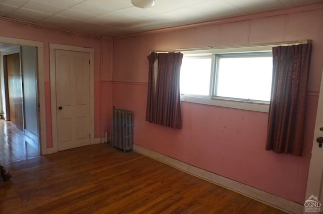 unfurnished room featuring radiator and hardwood / wood-style flooring