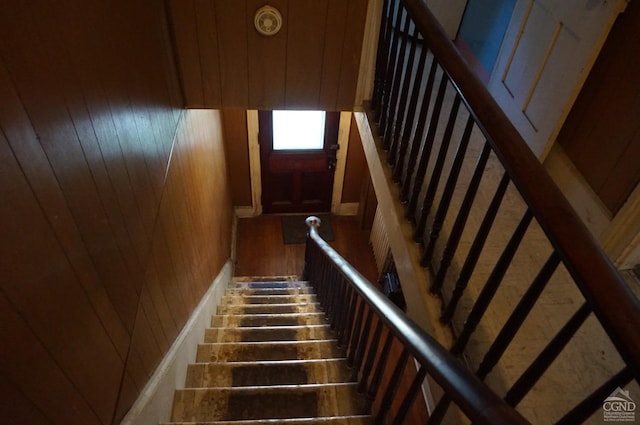 stairs with hardwood / wood-style flooring and wooden walls