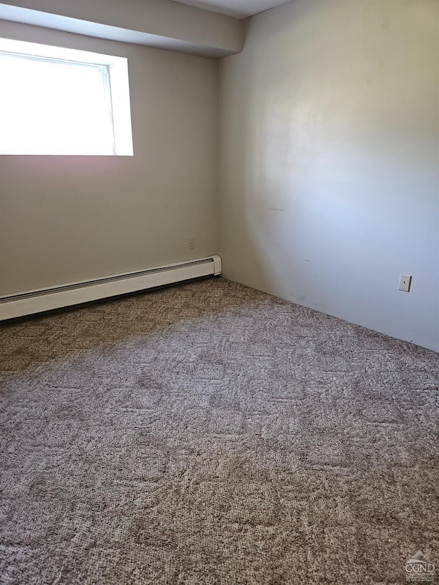 carpeted spare room with a baseboard heating unit