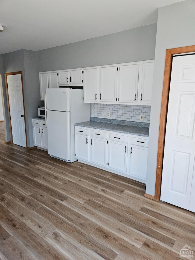 kitchen featuring white cabinets, light wood finished floors, and freestanding refrigerator