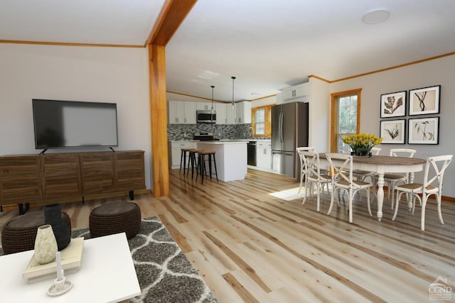 living room featuring vaulted ceiling, ornamental molding, and light hardwood / wood-style flooring