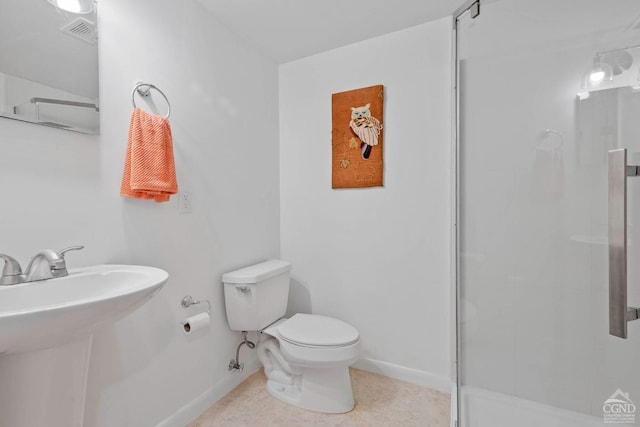 bathroom featuring toilet, a shower with door, and sink