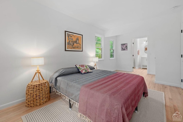 bedroom with ensuite bathroom and light wood-type flooring