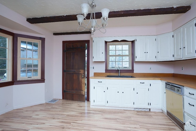 kitchen with a chandelier, beam ceiling, white dishwasher, white cabinets, and sink