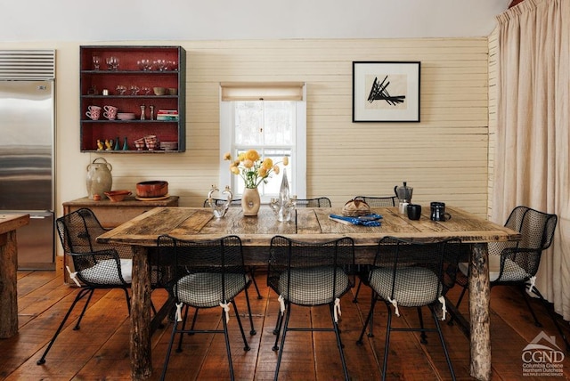 dining room with wood-type flooring and wooden walls