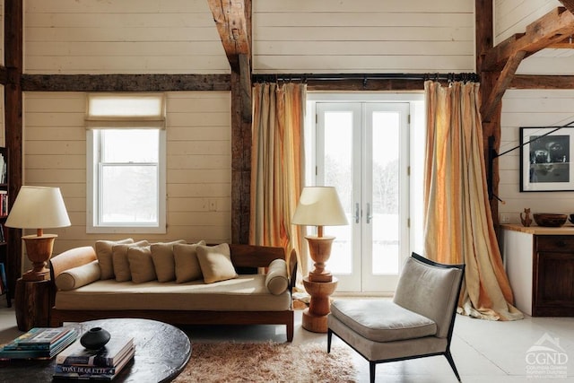 sitting room with a wealth of natural light, french doors, and wooden walls