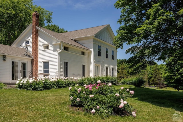 view of side of property with a yard, a chimney, and french doors