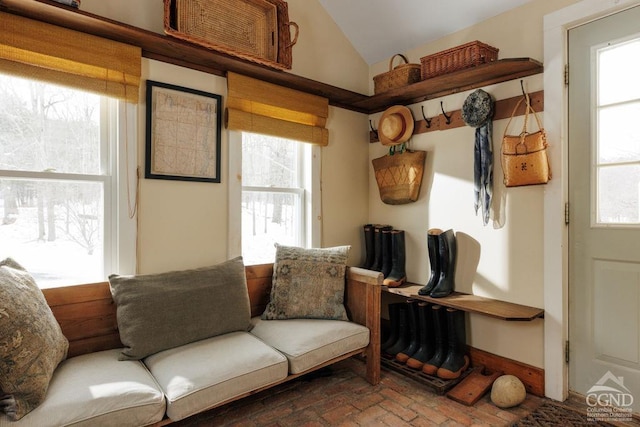 mudroom featuring brick floor, lofted ceiling, and baseboards