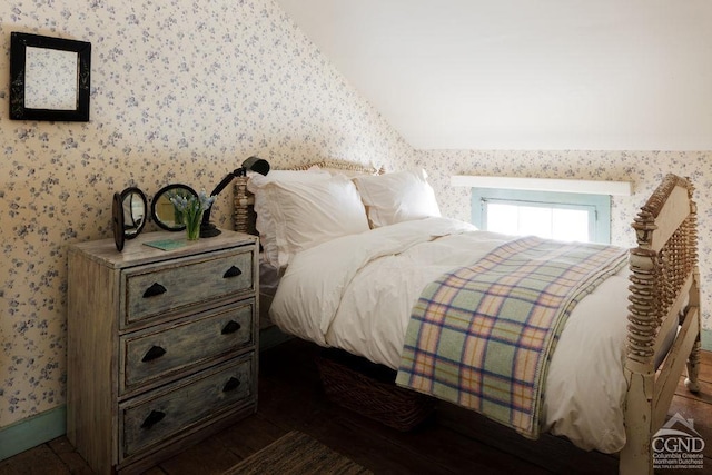 bedroom with lofted ceiling and wallpapered walls