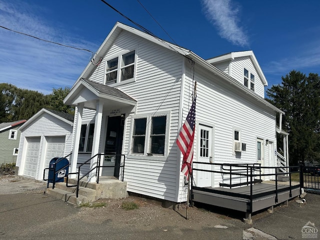 view of front facade featuring cooling unit, a garage, and an outbuilding