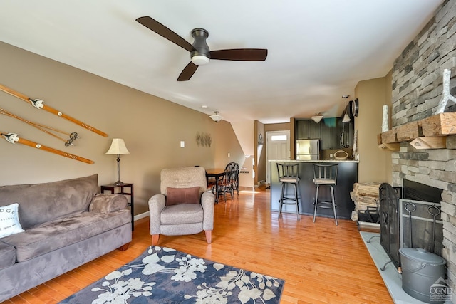 living room with ceiling fan, a fireplace, and wood-type flooring