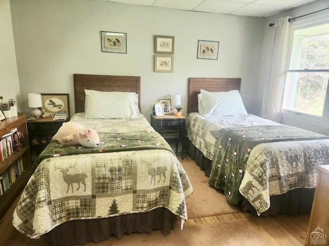 bedroom featuring wood finished floors and a drop ceiling