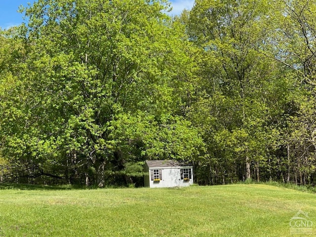 view of yard with an outbuilding, a storage shed, and a wooded view