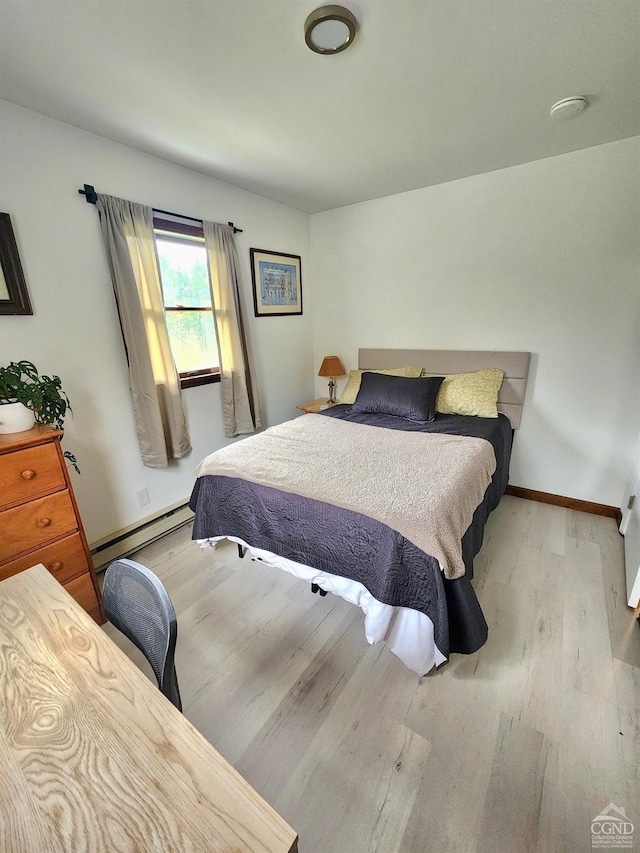 bedroom featuring baseboard heating, wood finished floors, and baseboards