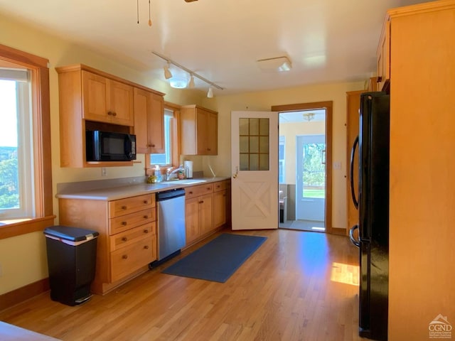 kitchen featuring black appliances, a healthy amount of sunlight, sink, and light hardwood / wood-style flooring