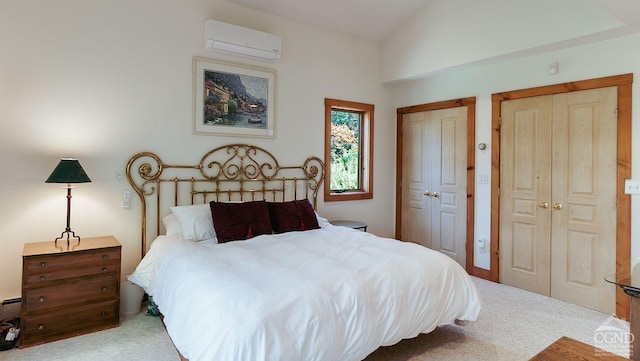 bedroom with vaulted ceiling, two closets, a wall unit AC, and light colored carpet