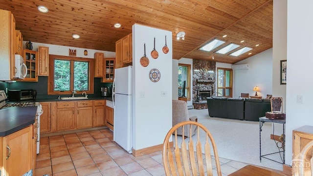 kitchen featuring white appliances, wooden ceiling, sink, vaulted ceiling with skylight, and a fireplace