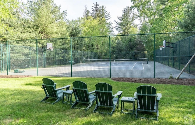 view of tennis court featuring a lawn, community basketball court, and fence