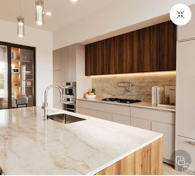 kitchen featuring modern cabinets, a sink, light stone counters, gas stovetop, and decorative backsplash