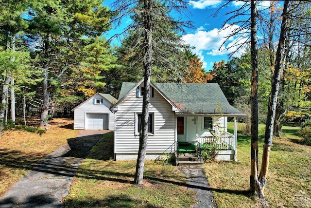 view of front of home with covered porch, an outbuilding, a garage, and a front lawn