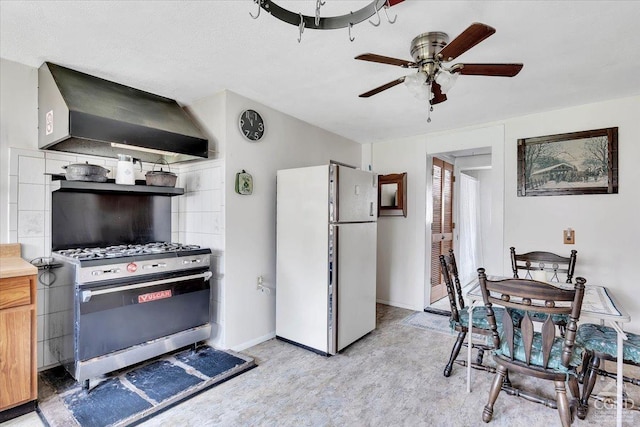 kitchen featuring freestanding refrigerator, extractor fan, stainless steel range with gas cooktop, light countertops, and a ceiling fan
