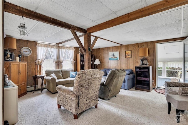living area with wooden walls, a baseboard radiator, light carpet, and a paneled ceiling