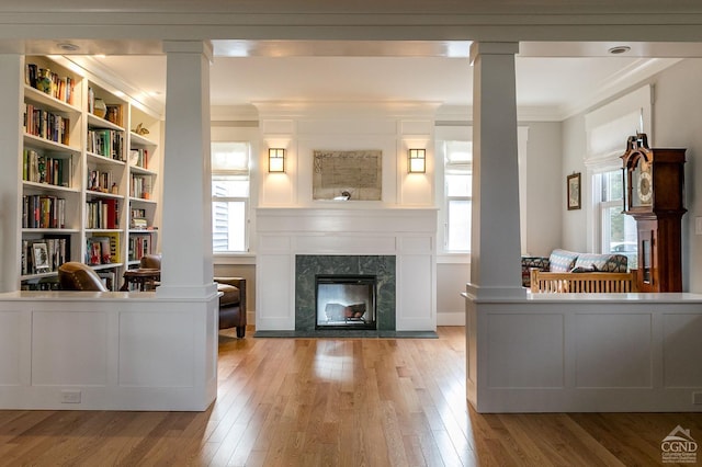 living room featuring ornate columns, a wealth of natural light, a high end fireplace, and light hardwood / wood-style floors