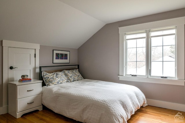 bedroom featuring lofted ceiling, multiple windows, and light hardwood / wood-style flooring