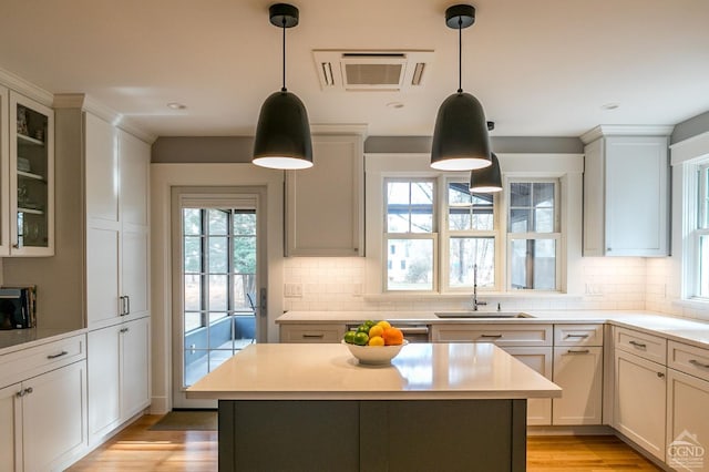 kitchen featuring white cabinets, pendant lighting, a kitchen island, and sink