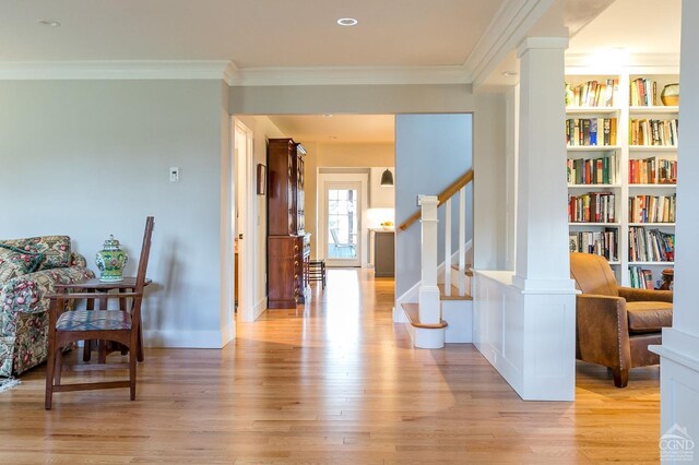 interior space featuring built in shelves, light hardwood / wood-style floors, ornate columns, and crown molding