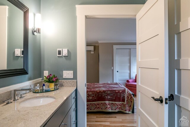 bathroom featuring a wall unit AC, hardwood / wood-style flooring, vanity, and ornamental molding