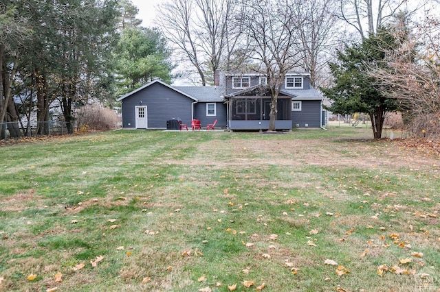 rear view of house featuring a sunroom and a yard