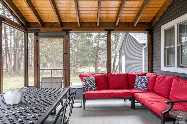 sunroom featuring vaulted ceiling with beams, a healthy amount of sunlight, and wood ceiling