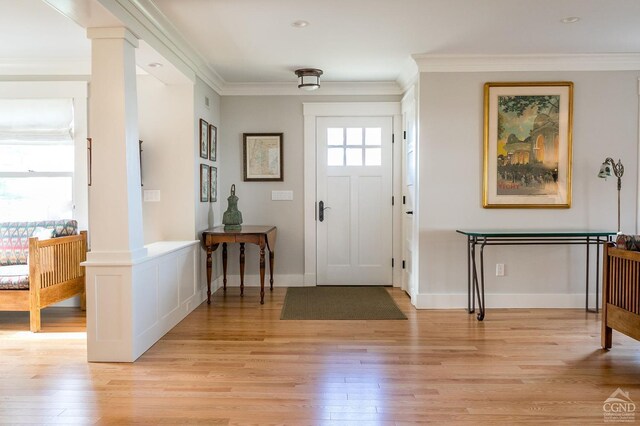 entryway featuring light hardwood / wood-style floors, ornate columns, and crown molding