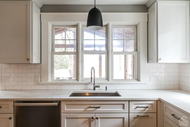 kitchen with pendant lighting, backsplash, stainless steel dishwasher, and sink