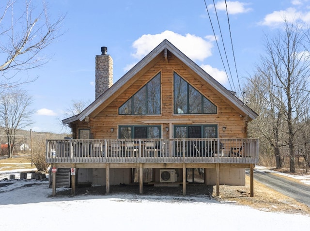 snow covered house featuring ac unit, a chimney, and a wooden deck