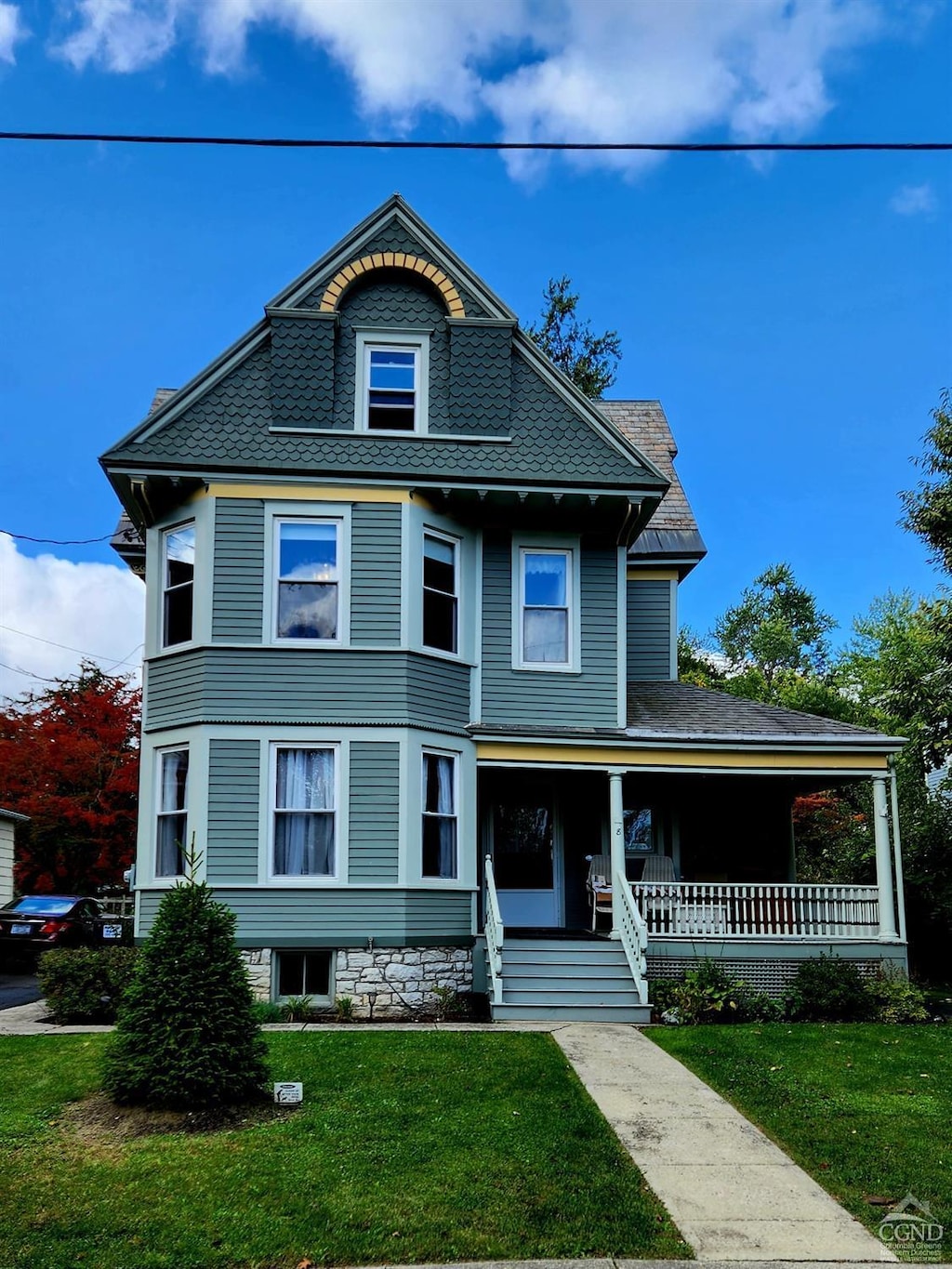 victorian-style house with a porch and a front lawn