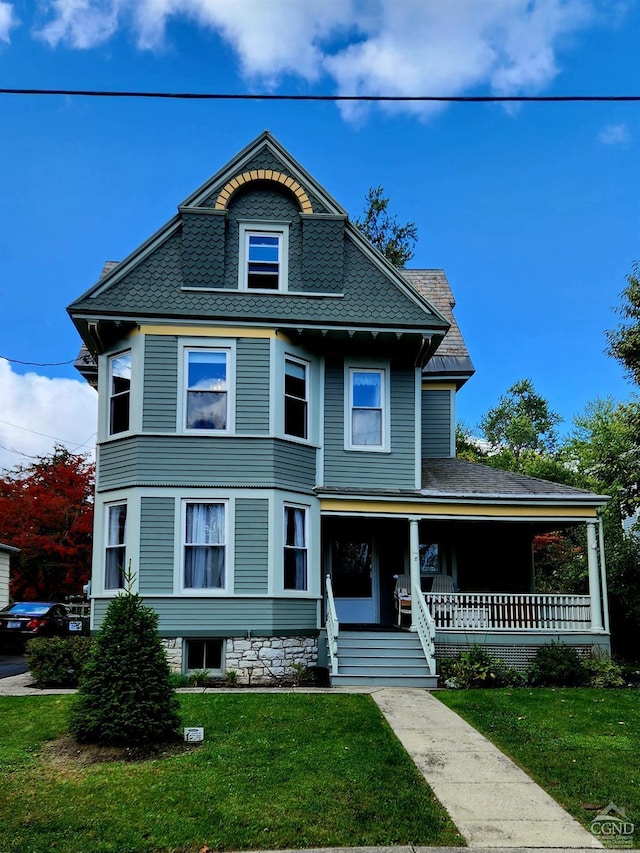 victorian-style house with a porch and a front lawn