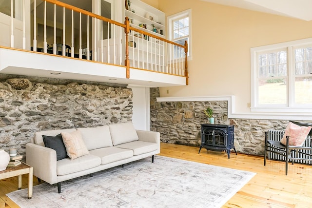 living room featuring a wood stove, a high ceiling, and hardwood / wood-style flooring