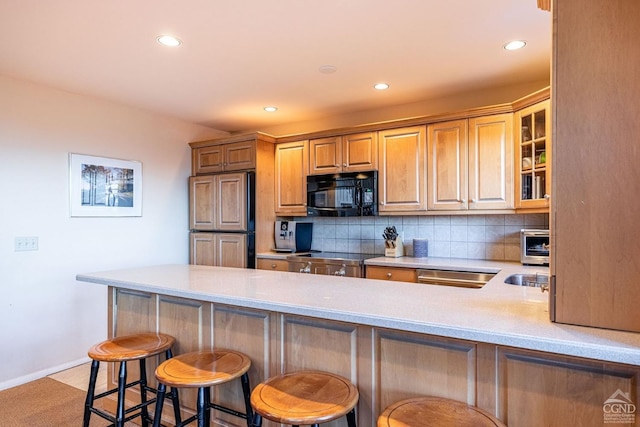 kitchen featuring a breakfast bar area, dishwasher, paneled built in refrigerator, backsplash, and kitchen peninsula