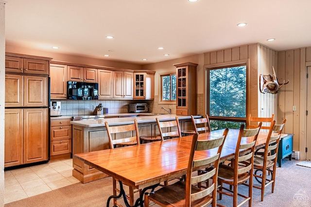 dining area featuring light colored carpet, sink, and wood walls