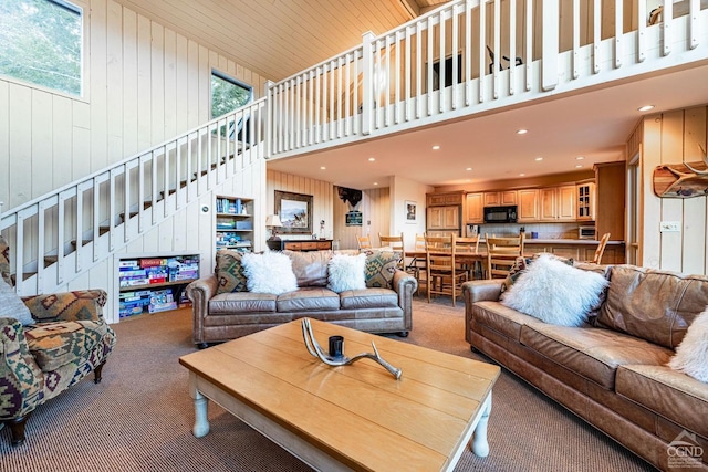 living room with carpet, a wealth of natural light, and wood walls