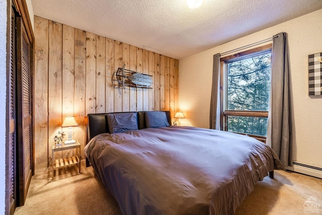 carpeted bedroom featuring a textured ceiling and wood walls