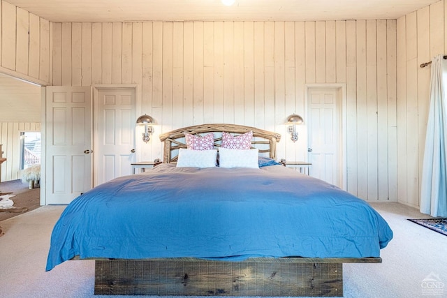 bedroom with light colored carpet and wood walls