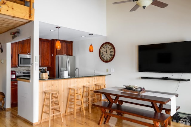 kitchen with pendant lighting, a breakfast bar area, backsplash, kitchen peninsula, and stainless steel appliances