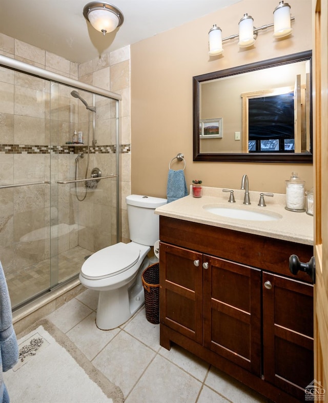 bathroom with vanity, toilet, a shower with shower door, and tile patterned flooring