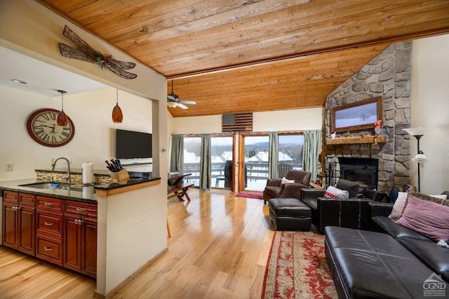 kitchen featuring sink, wood ceiling, a stone fireplace, light hardwood / wood-style floors, and decorative light fixtures