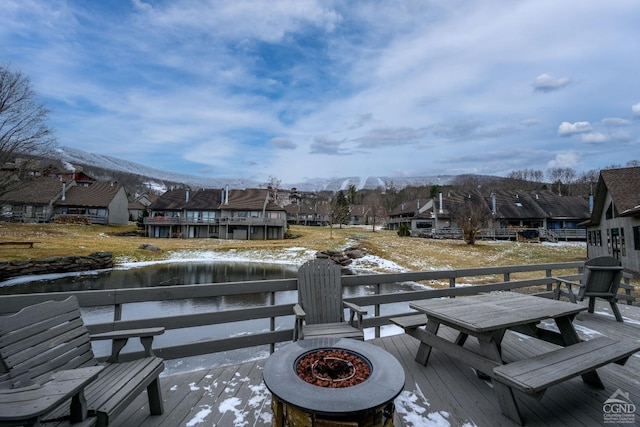 snow covered deck with a mountain view and an outdoor fire pit