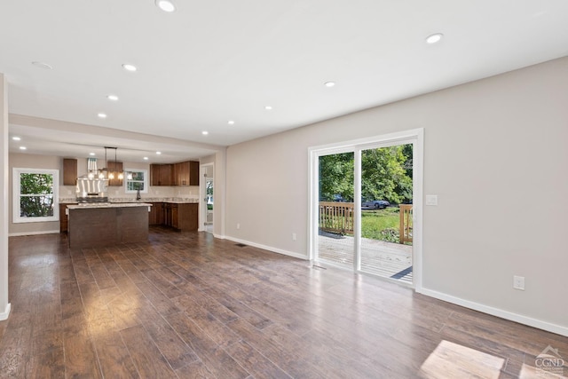 unfurnished living room with dark hardwood / wood-style floors and an inviting chandelier